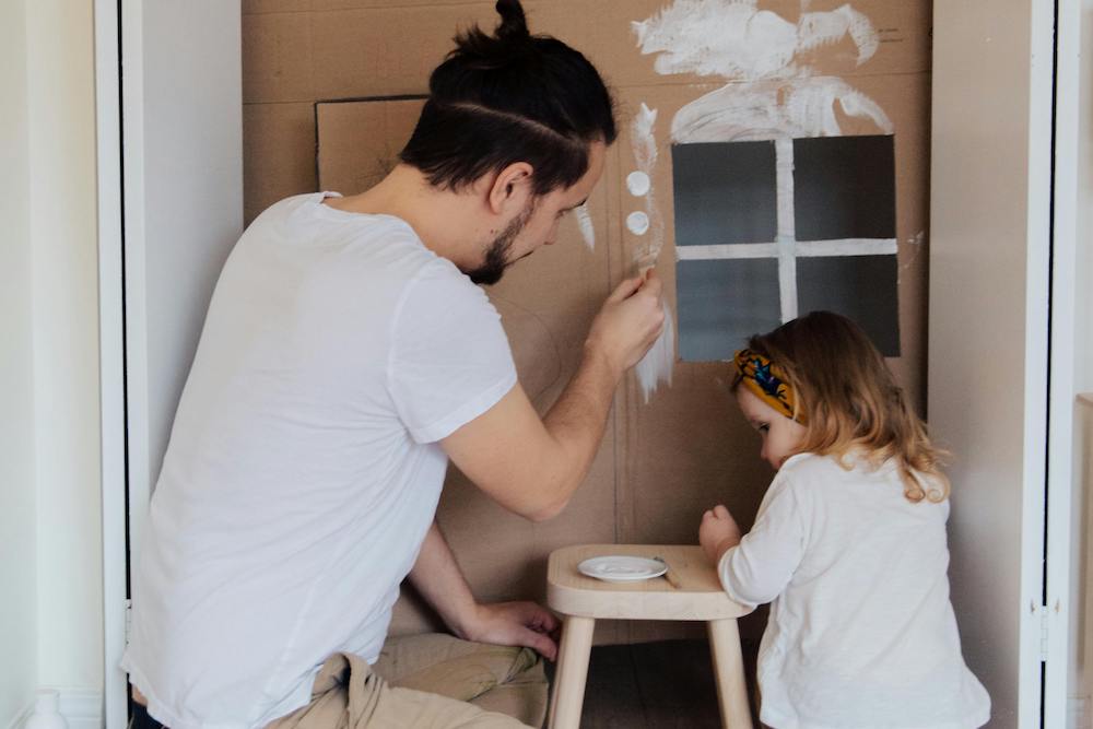 therapist painting cardboard house with child